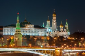 View of the Moscow Kremlin, lit by the evening lights. In the foreground of the Moscow River. View of the Armoury Chamber  and Cathedral. The photo shows the Tower with red stars and the stone bridge. View of the most famous sights of Russia.